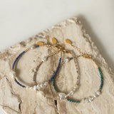 Three gold filled beaded bracelets on a textured stone surface