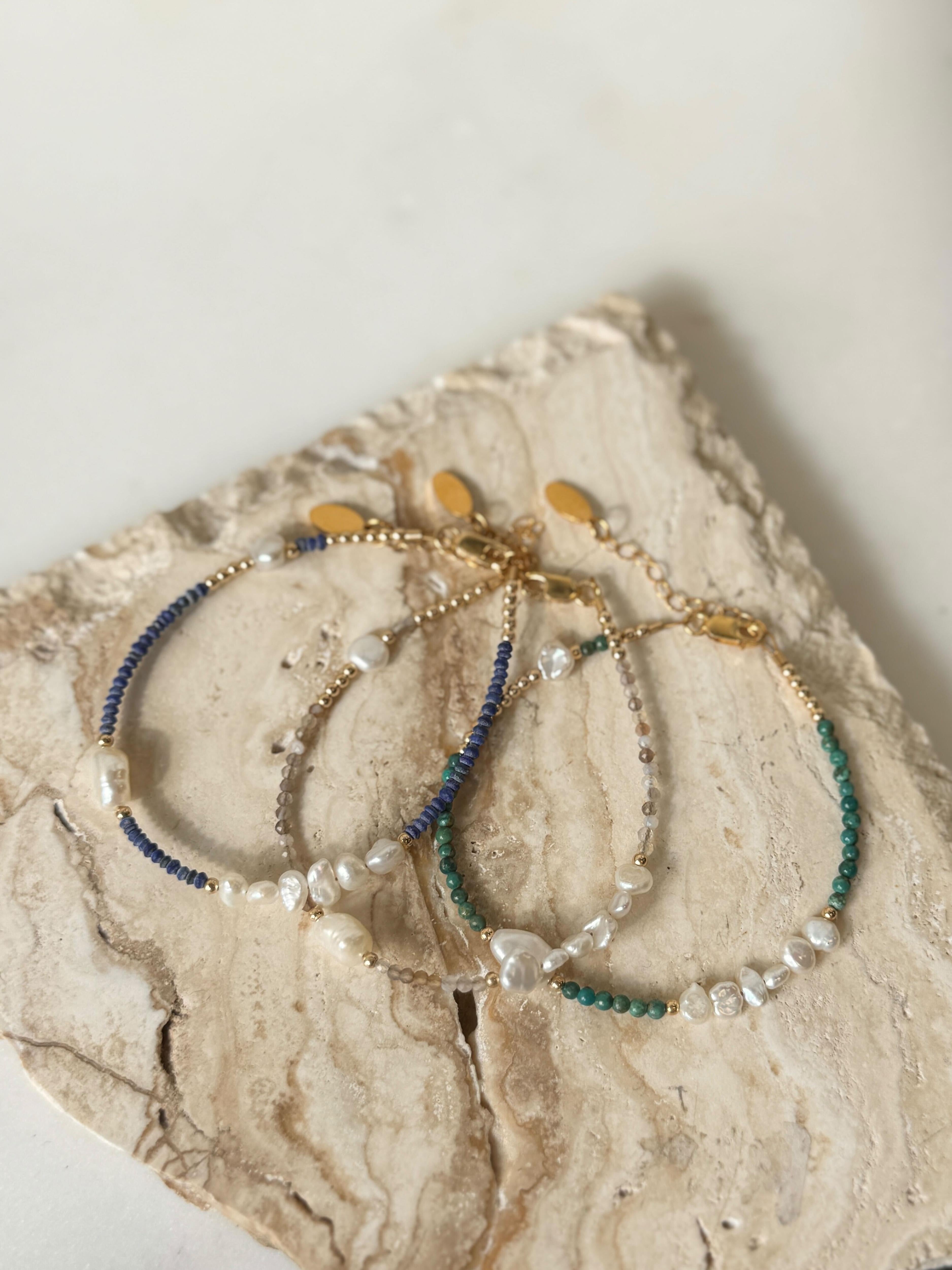 Three gold filled beaded bracelets on a textured stone surface