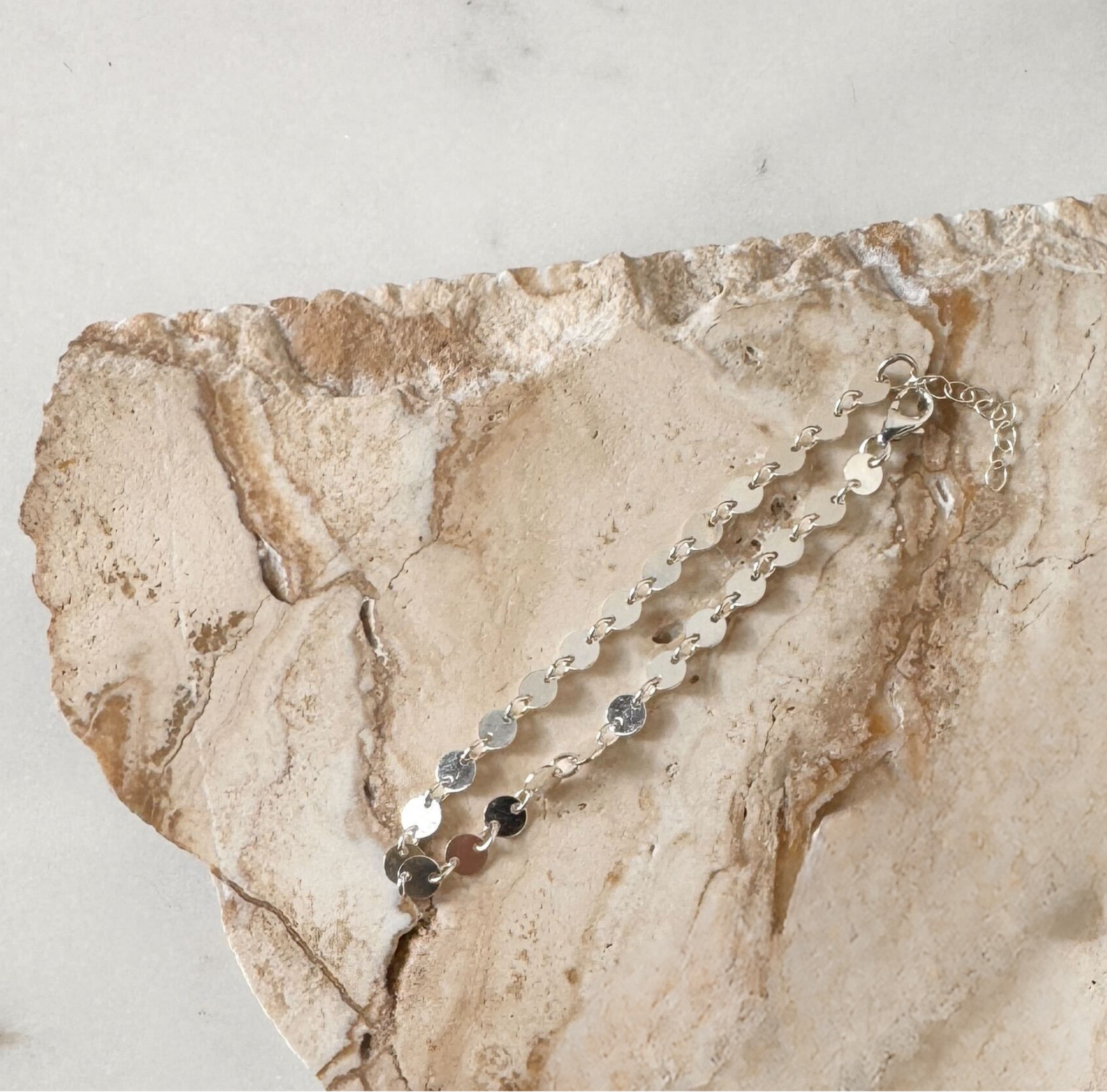 Silver chain necklace on a textured stone surface